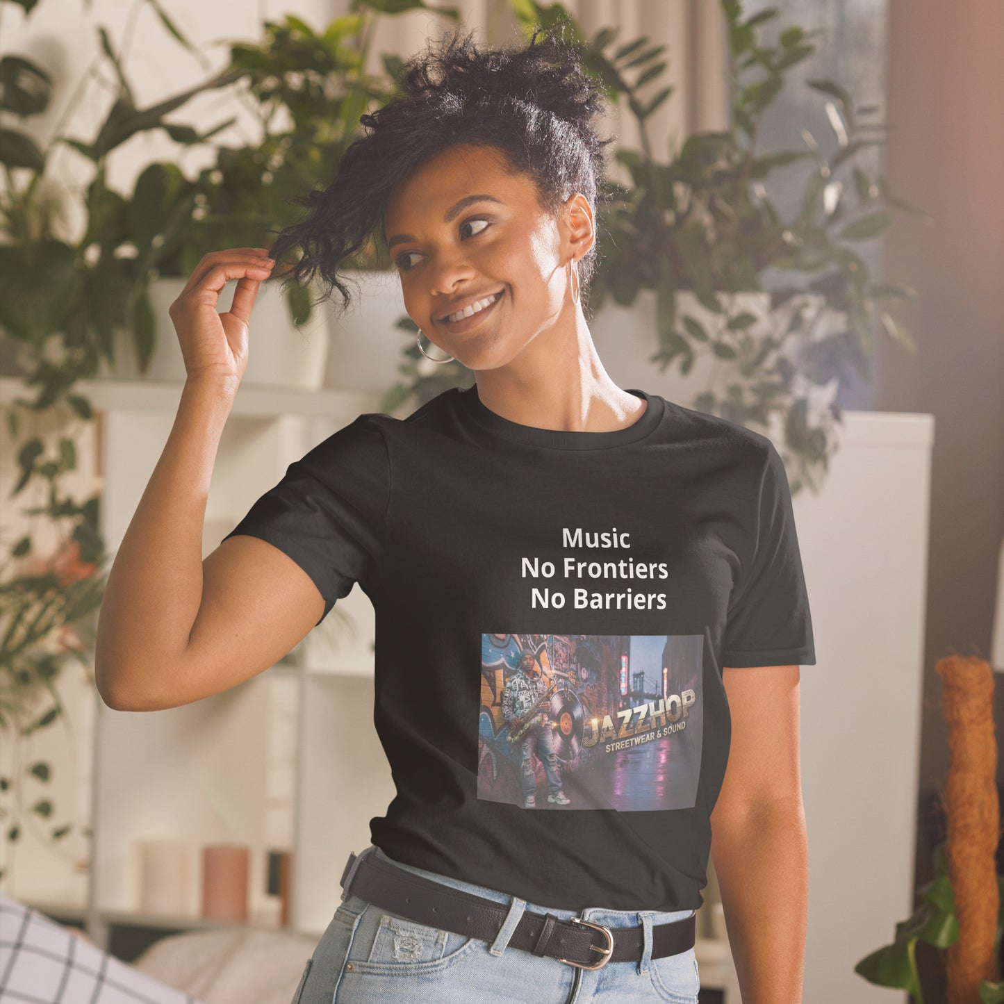 Person wearing a black t-shirt with 'Music No Frontiers No Barriers' text and a colorful graphic, standing in a room with plants.